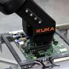 Der Kuka-Roboterarm greift auf das Mainboard von Fujitsu zu.