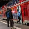 Reisende stehen im Hauptbahnhof München vor einer Regionalbahn.