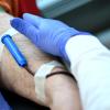 Eine Nadel mit Schlauch steckt in einem Arm eines Mannes bei einer Blutspendeaktion des DRK.