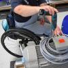 An einem Arbeitsplatz ist ein Mitarbeiter im Rollstuhl mit Montagearbeiten beschäftigt.