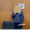 Im Landgericht Ulm hält sich ein Mann eine Akte vor das Gesicht. Der Angeklagte soll Ende Juni 2021 seinen Arbeitskollegen während einer Pause erstochen haben. 