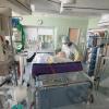 Ein Chefarzt untersucht in Schutzkleidung in einem isoliertem Intensivbett-Zimmer einen positiv getesteten Corona-Patienten.