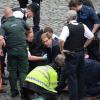 Der Staatssekretär Tobias Ellwood (Bildmitte) kümmert sich am Mittwoch in der Nähe des britischen Parlaments in London Großbritannien um einen verletzten Polizisten. 
