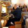 Organist Hans Stumpp an der Orgel und als Dirigent des Singkreises (im Hintergrund) während eines Auftrittes in der Holzschwanger Georgskirche. 	