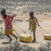 Zwei junge Mädchen ziehen Wasserbehälter auf dem Rückweg zu ihren Hütten im kenianischen Lomoputh.