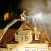 Feuerwehrleute löschen in der Coburger Altstadt ein brennendes Haus.  