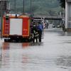 Zwei Einsatzkräfte stehen am Donnerstag (03.06.2010) in Passau (Niederbayern) neben einem Feuerwehrwagen in einer von der Donau überfluteten Straße.