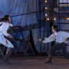 Den Mantel schon abgelegt, den Degen in der Hand: der Comte de Guiche (Paul Langmann) und Cyrano (Florian Gerteis) duellieren sich auf dem Kunstrasen im Martinipark des Staatstheaters Augsburg.