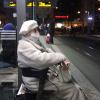 Die 91-jährige Susanne Köppendörfer muss am Kö auf die Straßenbahn warten, im Hintergrund ziehen die Corona-Kritiker vorbei.