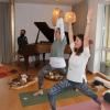 Monika Seifert (vorn) und Moni Hoffmann demonstrieren bei der Eröffnung des aurum loft einige klassische Yoga-Figuren. Dominik Kleinhenz, der Kurse wie „sound bath“ anbietet, begleitet am Flügel.