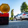 Ein Feuerwehrmann hat eine Straßensperre errichtet und leitet den Verkehr um den Einsatzort herum.