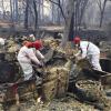 Freiwillige Rettungskräfte suchen in den Trümmern von Häusern, die dem "Camp"-Feuer zum Opfer gefallen sind, nach menschlichen Überresten.