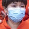 Eine chinesische Ärztin mit Mundschutzmaske hat Tränen in den Augen.