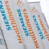 Das Logo und der Schriftzug des Medizintechnikkonzerns Siemens Healthineers stehen auf Fahnen vor der Unternehmenszentrale.
