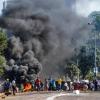 Plünderer stehen in Durban vor einem Einkaufszentrum neben einer brennenden Barrikade. 