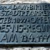 An der Südfassade der Kirche St. Martin in Günzburg erinnert ein Relief und eine Bronzetafel an Stadtpfarrer Adam Birner. Der Priester predigte gegen die Nazis. Am 13. April wurde er vermutlich im Augsburger Gefängnis ermordet.