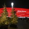 Beleuchtete Weihnachtsbäume stehen vor der Partie im Zugang zum Stadion.