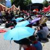 Teilnehmer einer Großdemonstration des Bündnisses «Stop G7 Elmau» schützen sich mit Schirmen gegen die Hitze.