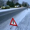 Mit einem Warndreieck wird die Straße nach einem Glätteunfall abgesichert.