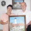 Die Künstlerin Helga Lorenz überreicht das Bild „Pfarrhof und Kirche Unterthürheim“ der Gemeinde Buttenwiesen. 2. Bürgermeister Christian Knapp bedankt sich herzlich für das Geschenk. Im Hintergrund das Bild „Rathaus Buttenwiesen“ von Helga Lorenz, das seit einigen Jahren als Blickfang vor dem großen Sitzungssaal des Gemeinderats angebracht ist. 