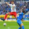 Augsburgs Rani Khedira und Hoffenheims Nico Schulz springen am Ball vorbei.