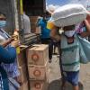Eine Frau mit Mundschutz macht sich in San Jose Calderas, Guatemala, mit einem Sack voll Hilfsgütern auf den Heimweg.