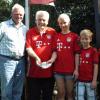 Strahlende Gesichter unter der Bayern-Fahne nach der Spende: (von links) Opa Reinhard, Bayern-Fan Rudi Tausend und die Enkel Celina und Maximilian. 	