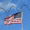 Eine US-Flagge hinter Zaun und Stacheldraht auf dem Marinestützpunkt Guantánamo Bay auf Kuba. Hier betreiben die USA seit mehr als 21 Jahren ein umstrittenes Gefangenenlager.