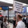 Der Berufspendler Thomas aus dem Raum Augsburg hält im Hauptbahnhof München (Bayern)ein Schild mit der Aufschrift "Machtkampf auf unserem Rücken? Nein!" in die Höhe.