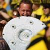 Ein BVB-Fan beißt in eine Meisterschale aus Pappe. Borussia Dortmund hat am 30. Spieltag der Fussball-Bundesliga einen großen Schritt in Richtung Titel gemacht. Die Schwarz-Gelben gewannen ihr Spiel gegen den SC Freiburg mit 3:0 (2:0). Konkurrent Bayer 04 Leverkusen verlor 1:5 in München. 