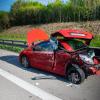 Einsatzkräfte der Feuerwehr stehen am Unfallort neben dem Autowrack.