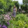 Regina Kaiser in ihrem Naturgarten in Reisch mit hochgewachsenen Gehölzen und Blumen wie Herbstanemonen und Phlox.