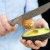 Schritt 3: Die Avocadohälfte mit Kern in eine Hand nehmen. Mit dem Messer kurz und fest in den Kern schlagen. Nun kann man ihn am Stück herausziehen.