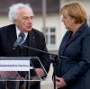 Max Mannheimer steht neben Angela Merkel im ehemaligen Konzentrationslager Dachau  und unterhält sich mit der Kanzlerin. 