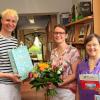 Logopädin Britta von Nordheim bei der Übergabe der Bücherspende, rechts im Bild Bücherei-Mitarbeiterin Marlen Emhofer, links Büchereileiter Johannes Schindlbeck.