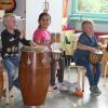 Paula Print betrachtet die verschiedenen Masken, die die Kinder während der Projektwoche an der Grundschule in Inchenhofen basteln (oben). Paula Print hat sich zwischen die Trommler geschmuggelt und staunt darüber, wie sie das Trommeln in ihrem Bauch spürt (unten). 	