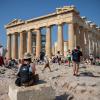 Touristen in Athen gehen an einem heißen Tag bei ihrem Besuch des Parthenon-Tempels auf dem Akropolis-Hügel.