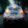 Nur verschwommen ist ein Auto durch eine regennasse Windschutzscheibe zu sehen.