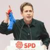 Kevin Kühnert, Bundesvorsitzender der Jusos, hält bei seiner Rede beim SPD-Bundesparteitag eine blaue Socke hoch.