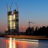 Mit Baukränen auf der Spitze hebt sich der im Bau befindliche Rohbau der "neuen EZB" vor dem Abendhimmel am Mainufer in Frankfurt ab. 