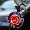 Ein Polizist hält bei einer Verkehrskontrolle eine Winkerkelle in der Hand.