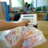 Ein Kind spielt mit Spielgeld – mehr echtes Geld müssen Eltern ab dem Herbst für die Kinderbetreuung in Buch bezahlen.