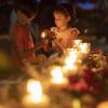 Zwei Kinder entzünden Kerzen während einer Mahnwache.