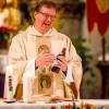 Pfarrer Herbert Kohler hält während einer Osternachtfeier in der St.-Peter-Kirche eine Flasche Weißbier in der Hand. Der Grund für das ungewohnte Bild: Unter den Osterkörben stand auch ein Kasten mit Weizen.  	