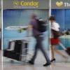 Passagiere gehen an einem Büro von Condor und Thomas Cook am Flughafen Palma de Mallorca vorbei.