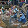 Teilnehmer des Fischertages springen mit ihren Keschern in den Stadtbach - allerdings sind Frauen nicht zugelassen.