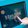 Eine Frau zieht sich an einem Fahrschein-Automaten ein 9-Euro-Ticket.