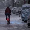 Ein Mann fährt in München mit seinem Fahrrad über eine schneebedeckte Straße.
