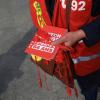Ein Mitglied einer Gewerkschaft verteilt vor dem Spiel rote Karten mit der Aufschrift «Nein zur Rente mit 64 Jahren».