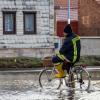 Ein Feuerwehrmann auf einem Fahrrad in einer überschwemmten Straße in Windehausen.